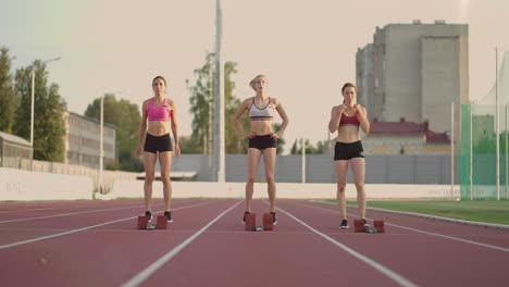Three-female-track-and-water-athletes-start-the-race-at-the-stadium-in-running-pads-at-a-sprint-distance.-Women-track-and-track-and-file-runners-running-in-the-stadium